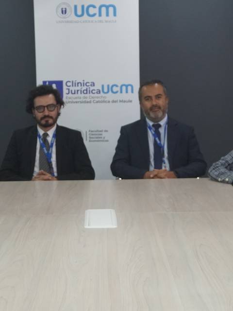 Un grupo de estudiantes y profesores posan juntos en una sala de reunión de una clínica jurídica.