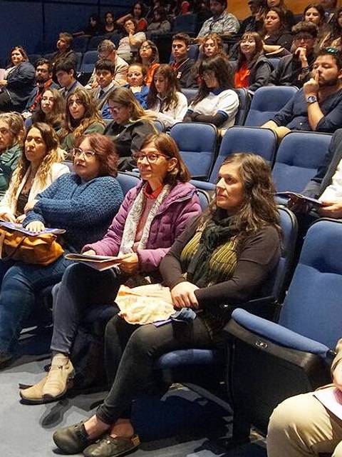 Una audiencia atenta sentada en un auditorio durante una presentación.