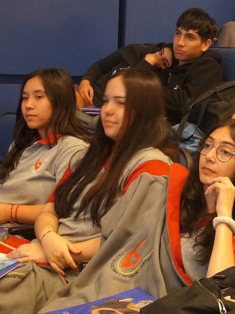 Un grupo de estudiantes sentados en un auditorio durante un evento escolar.