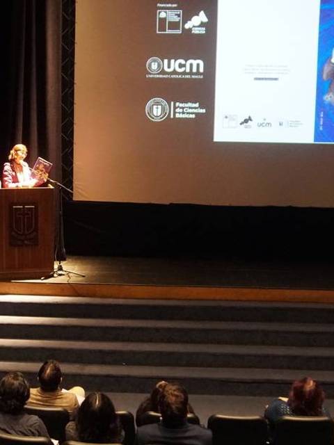 Una presentación en un auditorio con un ponente frente a una audiencia sentada.