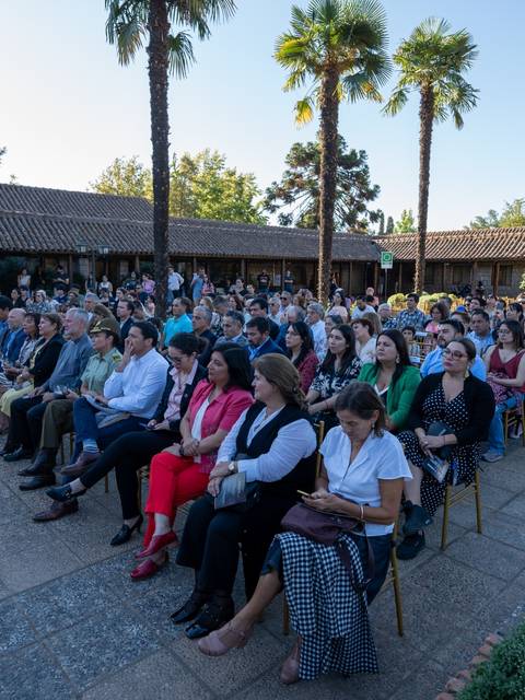 Una multitud de personas sentadas en un jardín durante un evento al aire libre.