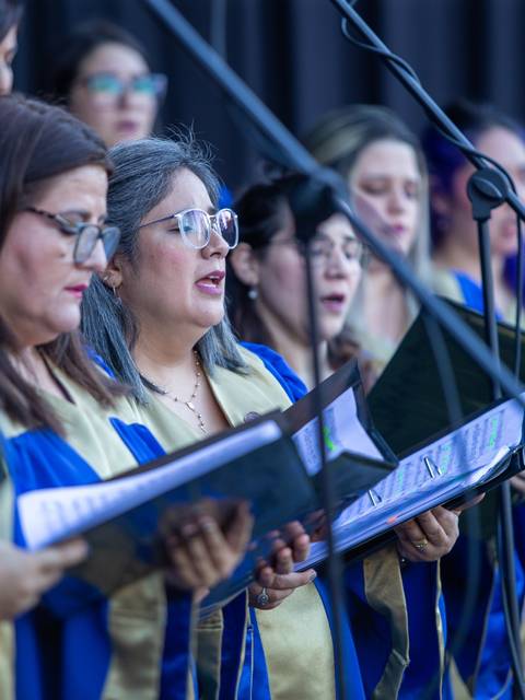 Un grupo de cantantes en un coro realiza una presentación con vestimenta colorida.