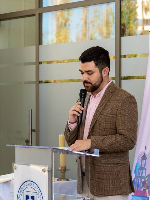 Una persona se encuentra hablando en un micrófono frente a un atril en un evento formal.