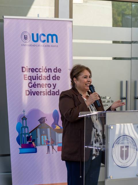 Una mujer habla frente a un podio en un evento sobre género y diversidad en una universidad.