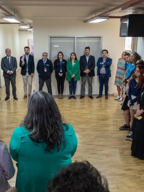 Un grupo de personas asisten a un evento en un salón con murales de presentación.