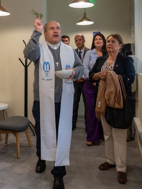 Un sacerdote realiza un ritual en un espacio interior, mientras un grupo de personas lo observa atentamente.