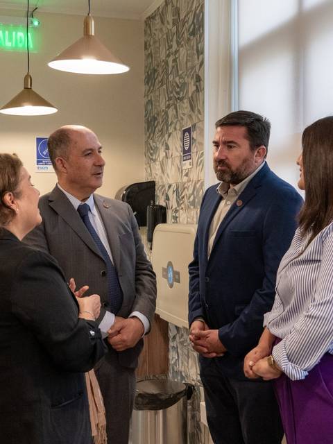 Cuatro personas conversando en un ambiente informal dentro de un edificio.