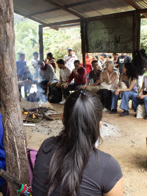 Un grupo de personas se reúne alrededor de un fuego en un espacio al aire libre.