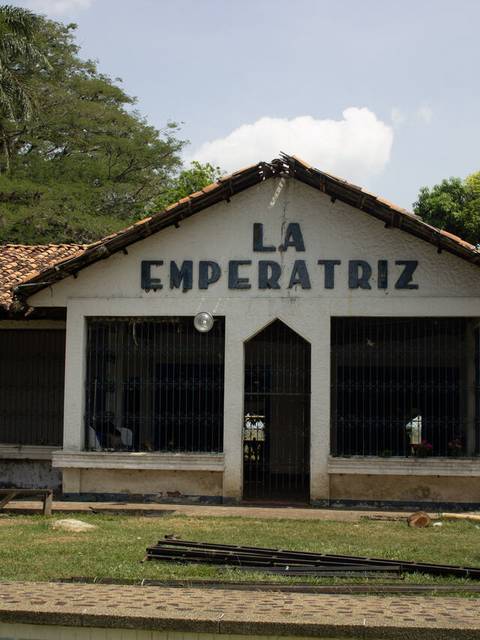 Una construcción con el letrero 'La Emperatriz' y un entorno natural.