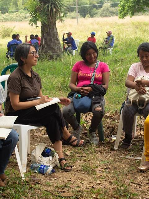 Un grupo de personas sentadas al aire libre durante una actividad comunitaria.