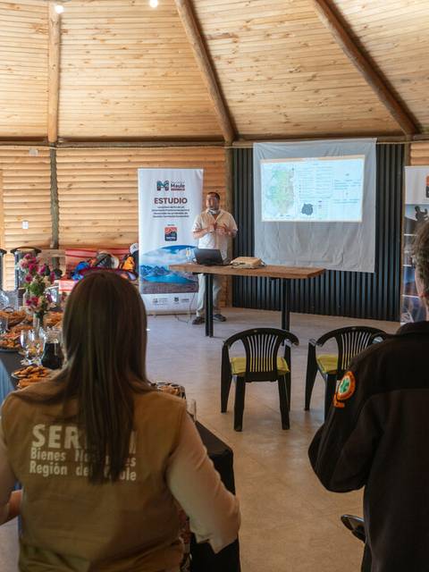 Una presentación en un espacio de reunión con un grupo de personas escuchando atentamente.