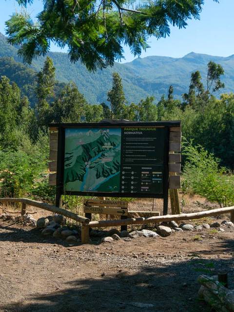 Un panel informativo en un entorno natural con montañas al fondo.