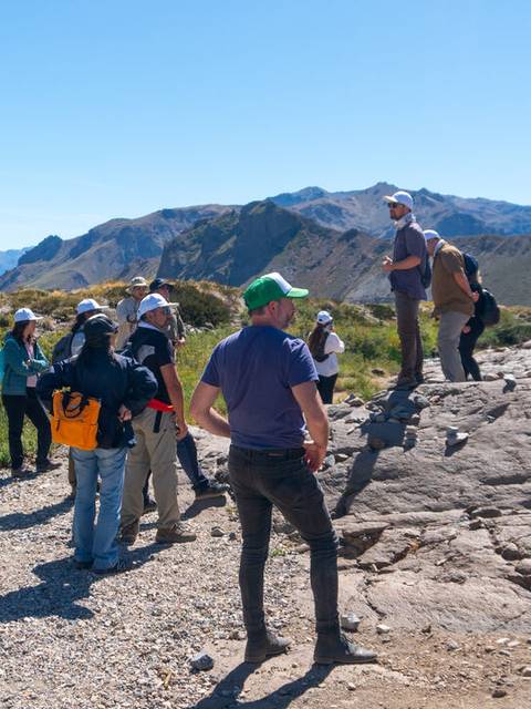 Un grupo de personas observa el paisaje en una zona montañosa durante un día soleado.