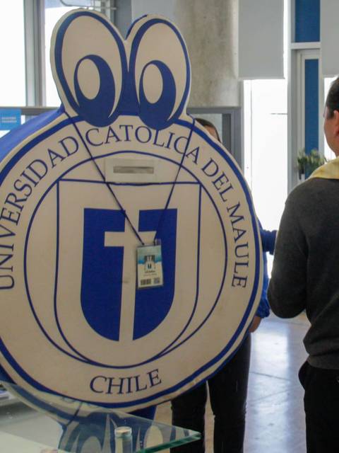 Persona interactuando con un personaje disfrazado que representa el logo de la Universidad Católica del Maule en Chile.