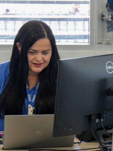 Una mujer sonriente trabaja en su computadora en una oficina moderna.