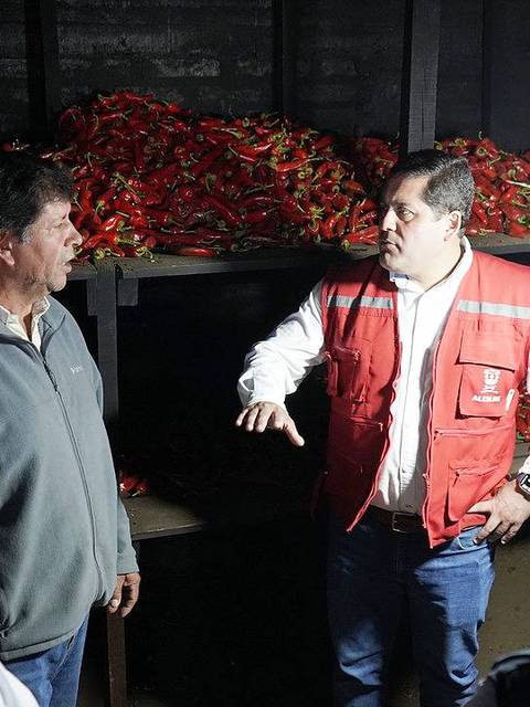 Un grupo de personas discutiendo en un almacén lleno de chiles.