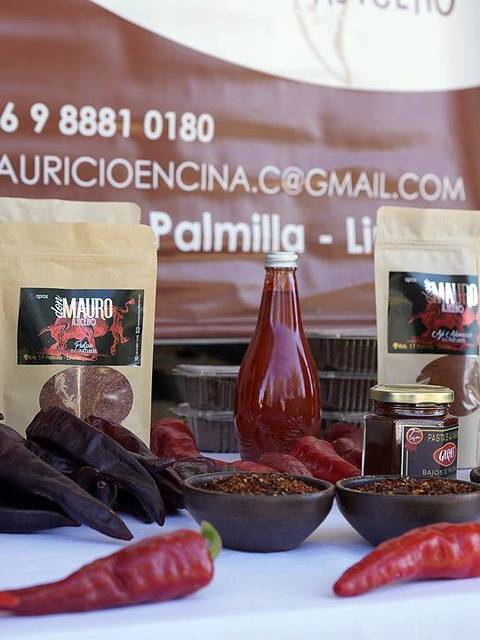 La imagen muestra una variedad de productos alimenticios a base de chiles, incluyendo salsas y especias, dispuestos sobre una mesa.