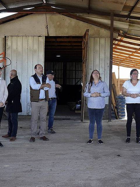Un grupo de personas se encuentra de pie frente a un edificio rural en un ambiente de trabajo.