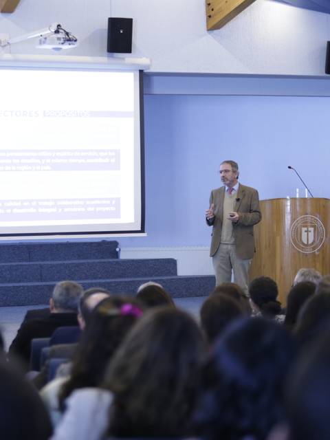 Un presentador está dando una charla en un auditorio frente a un público atento.