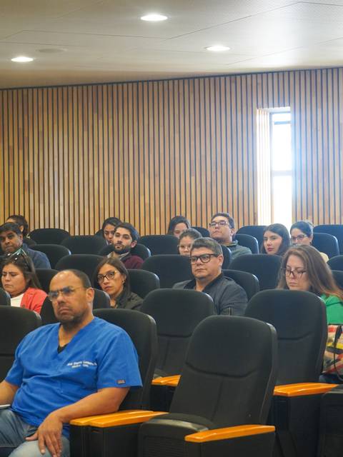 Un grupo de personas sentadas en un auditorio durante una presentación.