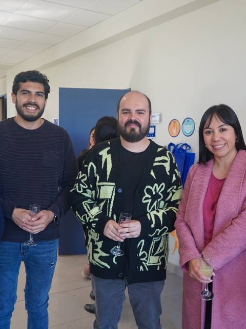 Un grupo de cinco personas posando sonrientes en un ambiente interior, probablemente en un evento social.