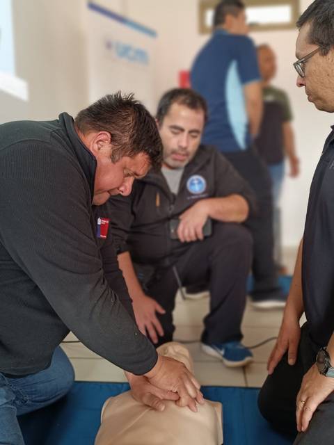 Un grupo de personas está realizando maniobras de resucitación cardiopulmonar sobre un maniquí en una capacitación.