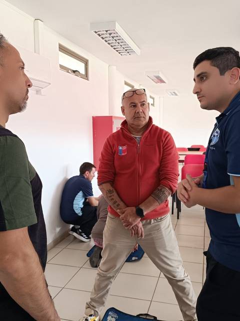 Tres hombres conversan en una sala de reuniones.