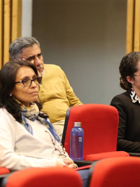Un grupo de personas sentadas en un auditorio prestando atención a una presentación.
