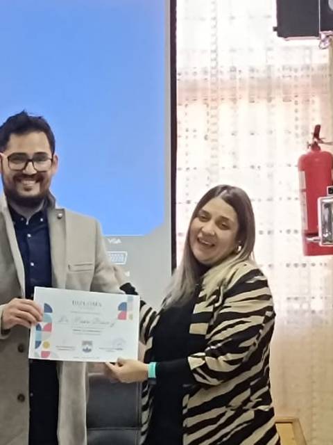 Una persona entrega un certificado a otra en un ambiente académico.