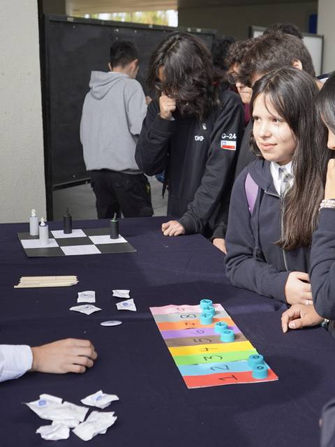 Un grupo de estudiantes interactúa con un presentador en una feria de ciencias.
