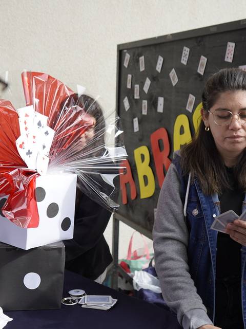 Una mujer cuenta cartas mientras dos personas la observan en un evento.