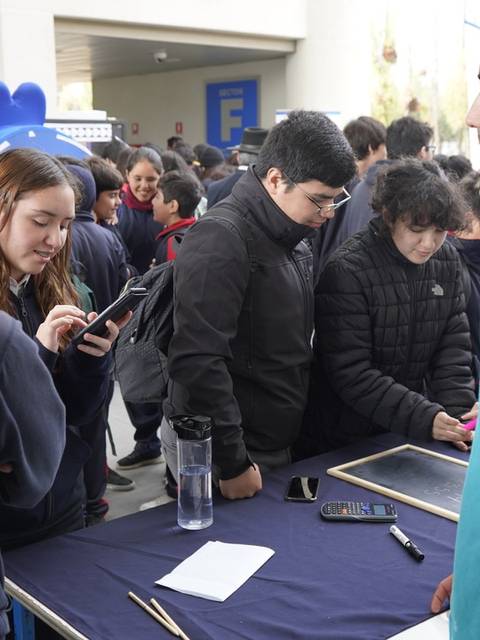 Un grupo de personas se reúne en un evento, interactuando y utilizando dispositivos móviles.