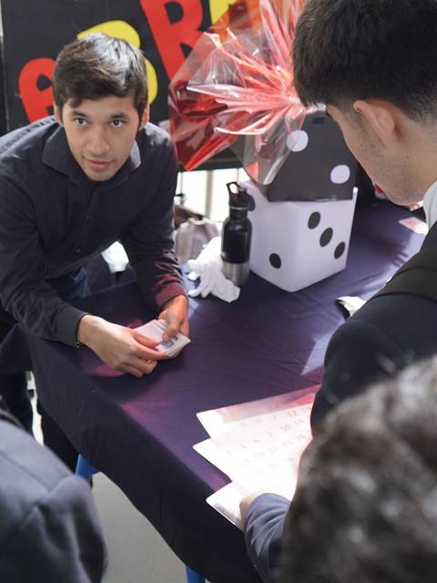 Un grupo de estudiantes observa atentamente a un profesor que les muestra algo en una mesa.