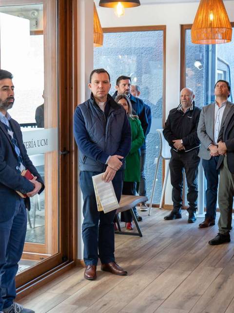Un grupo de personas asiste a un evento en una cafetería, mientras un hombre se prepara para hablar.
