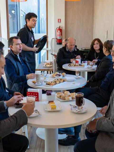 Grupo de personas sentadas en una mesa disfrutando de un desayuno en una cafetería.