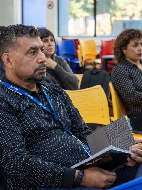 Una persona con una libreta sigue atentamente una presentación en un evento.