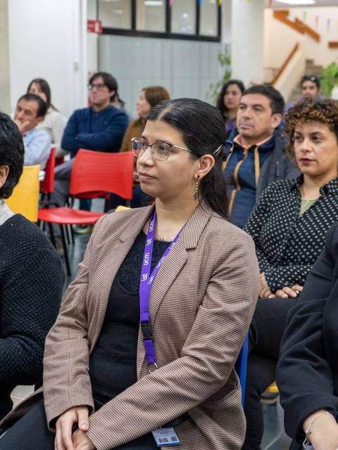 Un grupo de personas sentadas en un auditorio, escuchando atentamente.