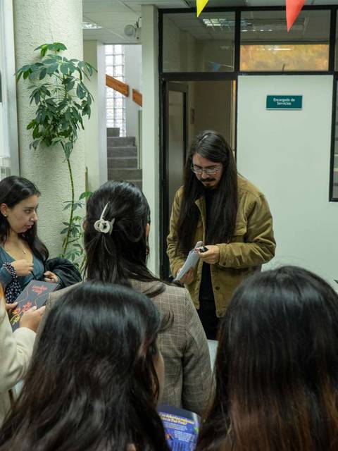 Un grupo de personas se reúne en un espacio interior decorado con globos y banderas.