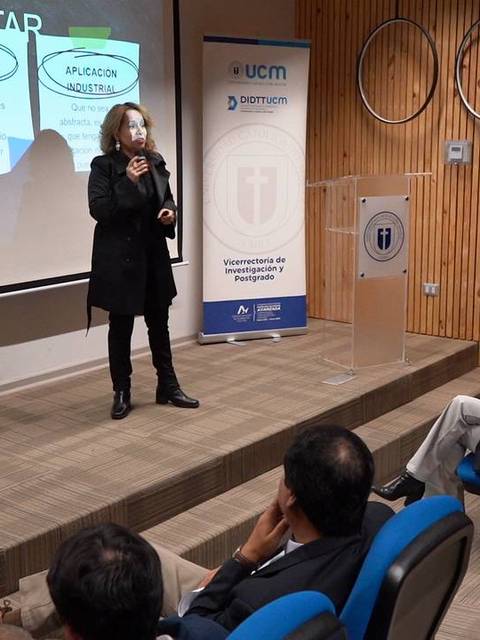 Una mujer habla en una conferencia sobre patentes ante una audiencia sentada.