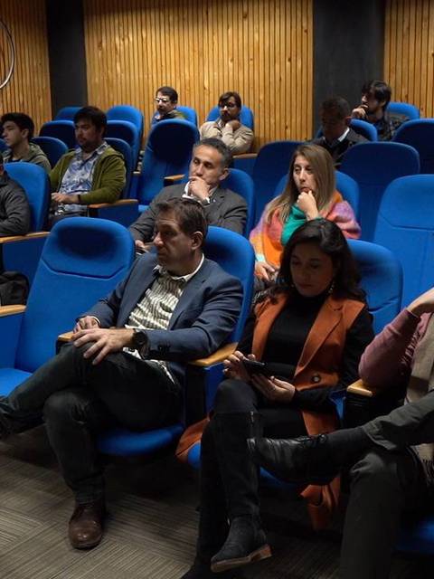 Una sala de conferencias con audiencia observando atentamente.