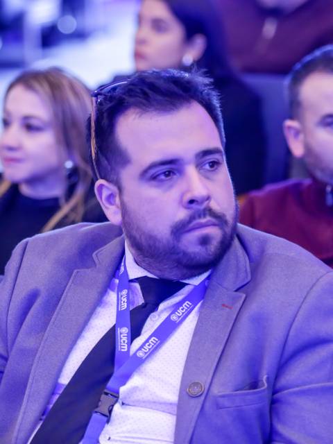 Un grupo de personas en un evento sentadas en un auditorio, con una iluminación azul suave.