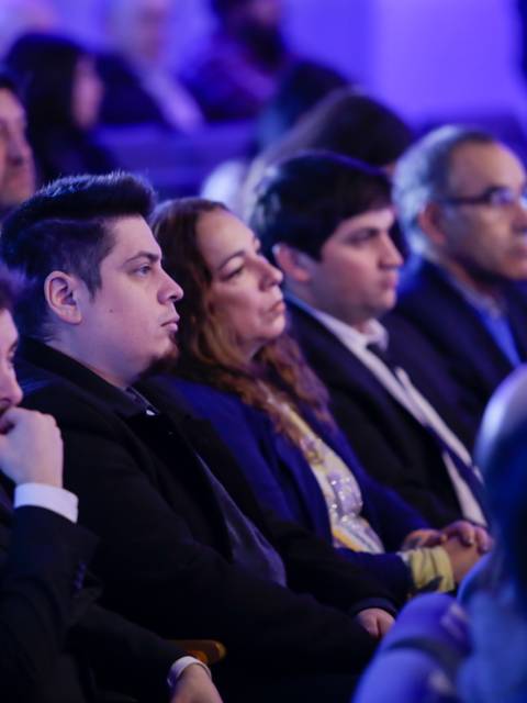 Un grupo de personas sentadas en un evento observando atentamente.