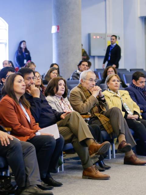 Un grupo de personas escuchando atentamente durante una conferencia en un auditorio.