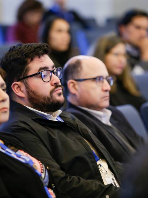Un grupo de personas escuchando atentamente durante un evento en un auditorio.