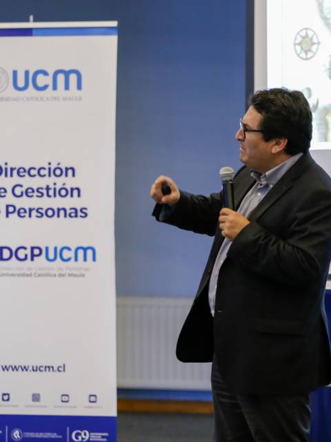 Un hombre está dando una presentación en un evento académico ante una audiencia.