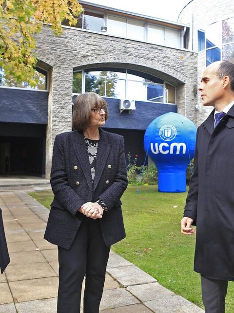 Tres personas conversan en un ambiente exterior frente a un edificio moderno.