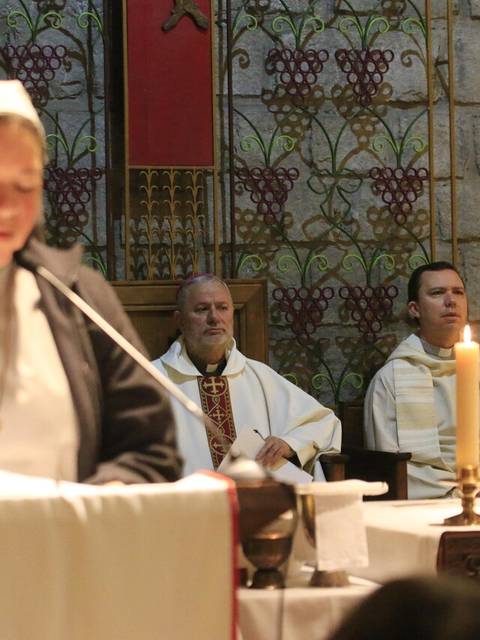 Un grupo religioso participa en una ceremonia con una persona leyendo al frente.