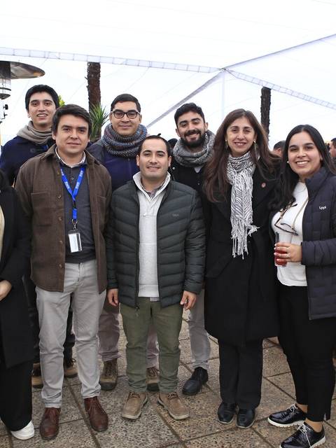 Un grupo de personas posando juntas en un evento al aire libre bajo una carpa.