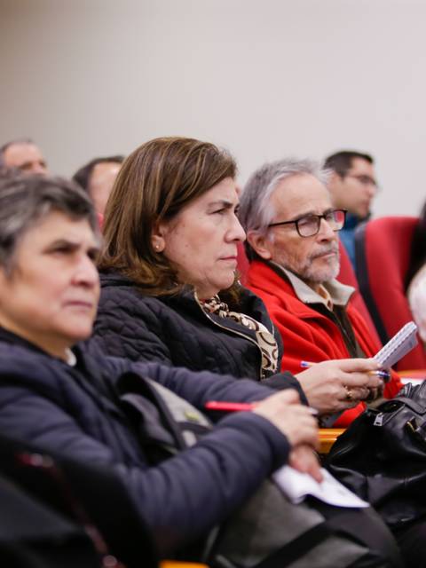 Un grupo de personas sentadas en un auditorio escuchando atentamente.