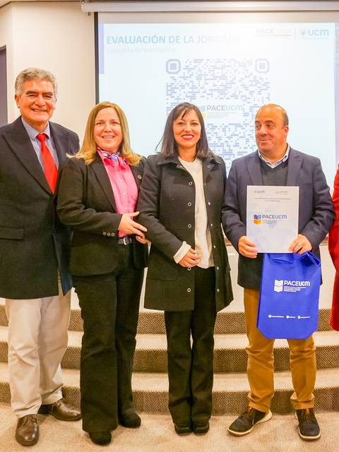 Un grupo de personas posando en un evento oficial con diplomas y carteles.